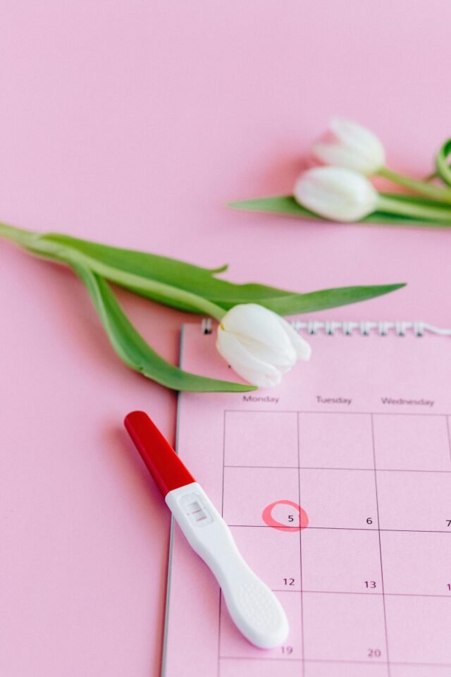 A positive pregnancy test on a pink calendar with tulips. Symbol of new beginnings.